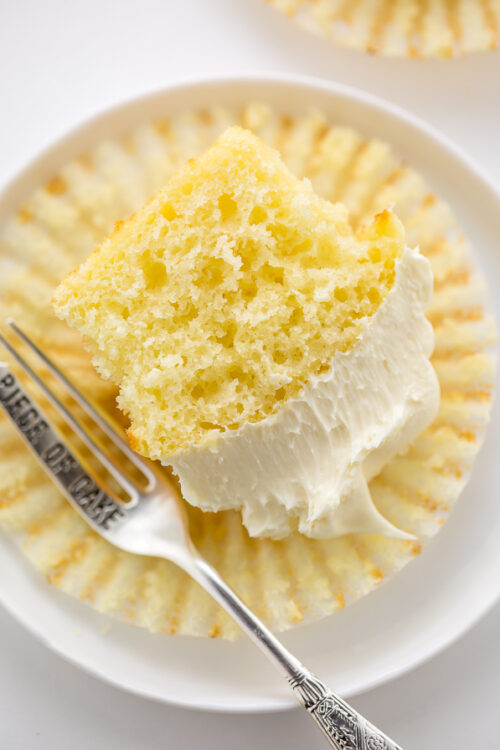 Vanilla cupcake topped with vanilla buttercream sliced in half.