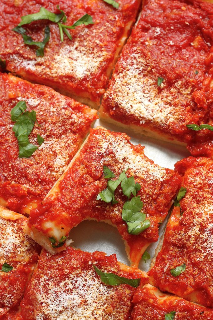 Slice of tomato pie topped with grated cheese.