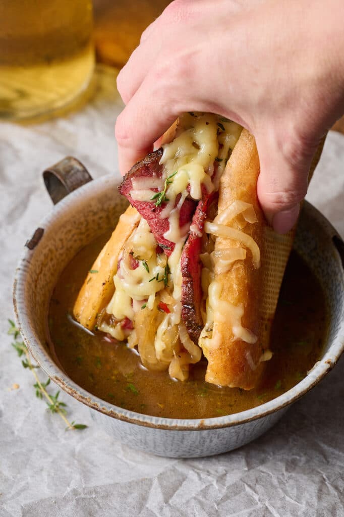 French dip being dunked into au jus.