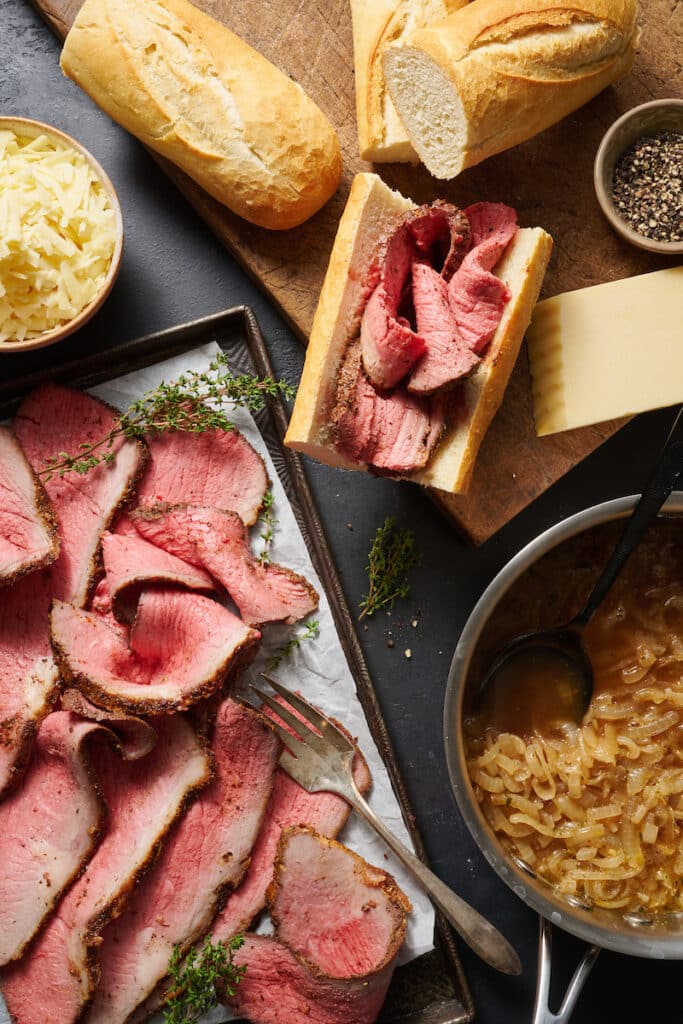 Ingredients for French dip sandwiches on a baking sheet.