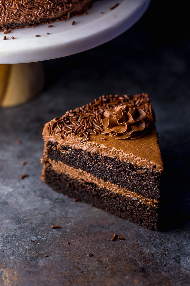 Slice of chocolate cake on a dark table top.