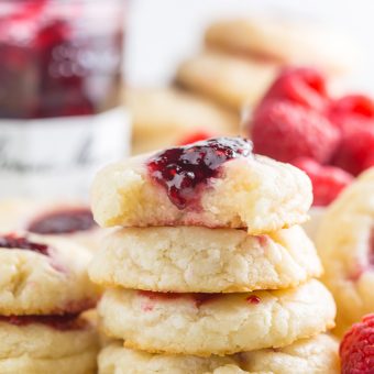 Raspberry thumbprint cookies in a stack on a wire cooling rack.