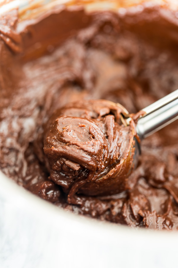 Cookie batter being scooped out of white bowl.