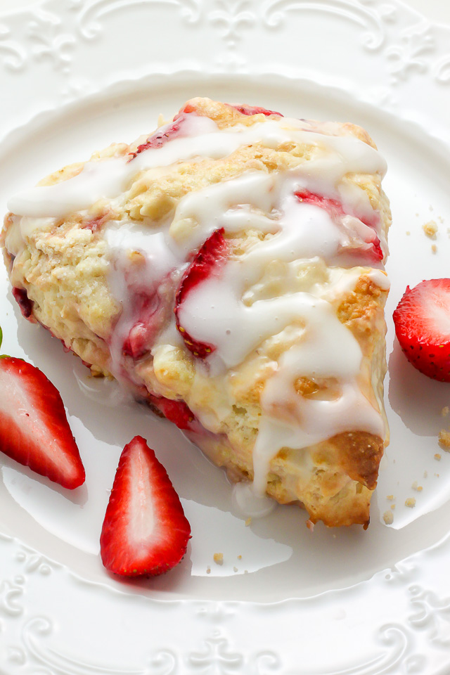 Strawberry scone with creamy glaze on a white plate.