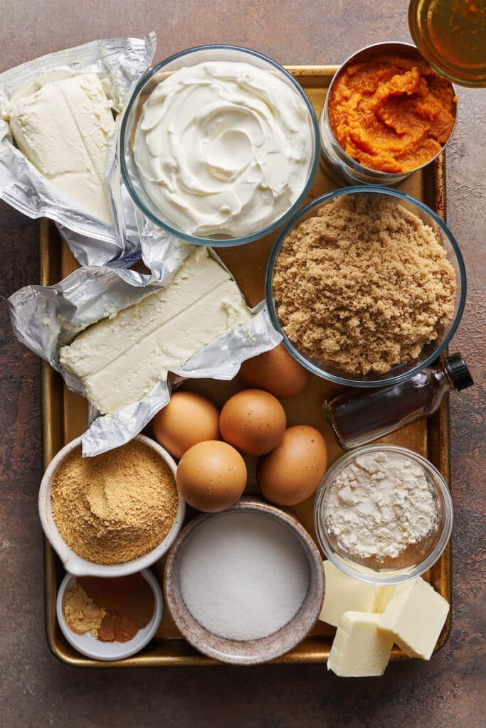 Ingredients for pumpkin cheesecake on a baking sheet.