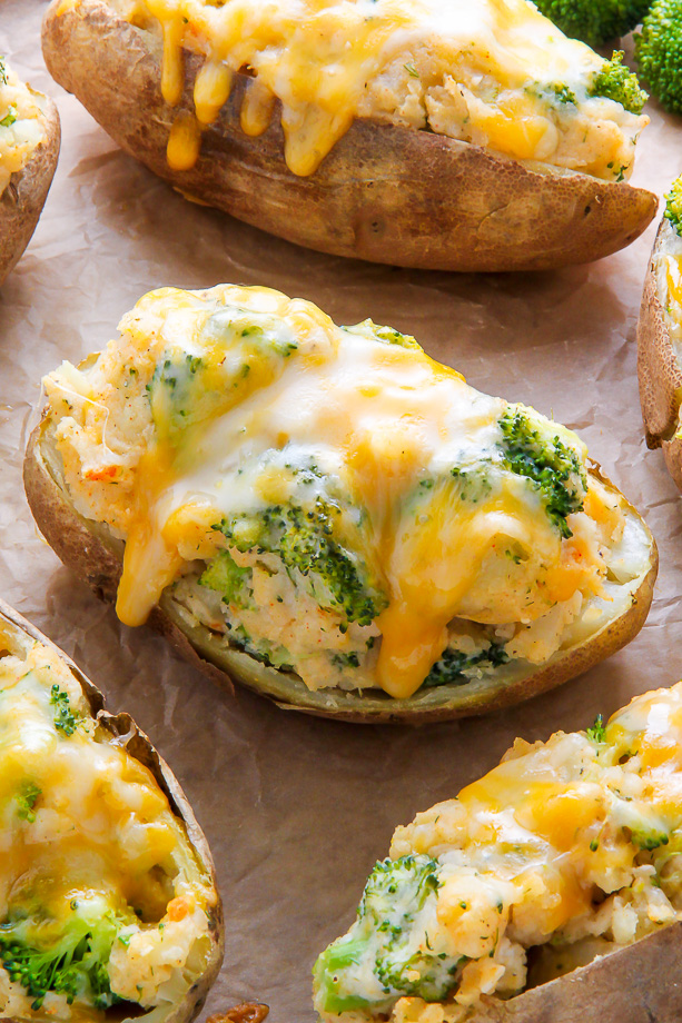 Twice-baked potatoes on parchment paper topped with broccoli and cheese.