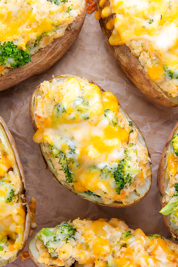 Twice-baked potatoes on parchment paper topped with broccoli and cheese.