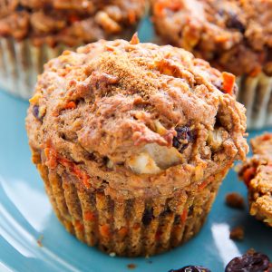 Morning glory muffin on a blue plate topped with shredded carrots.