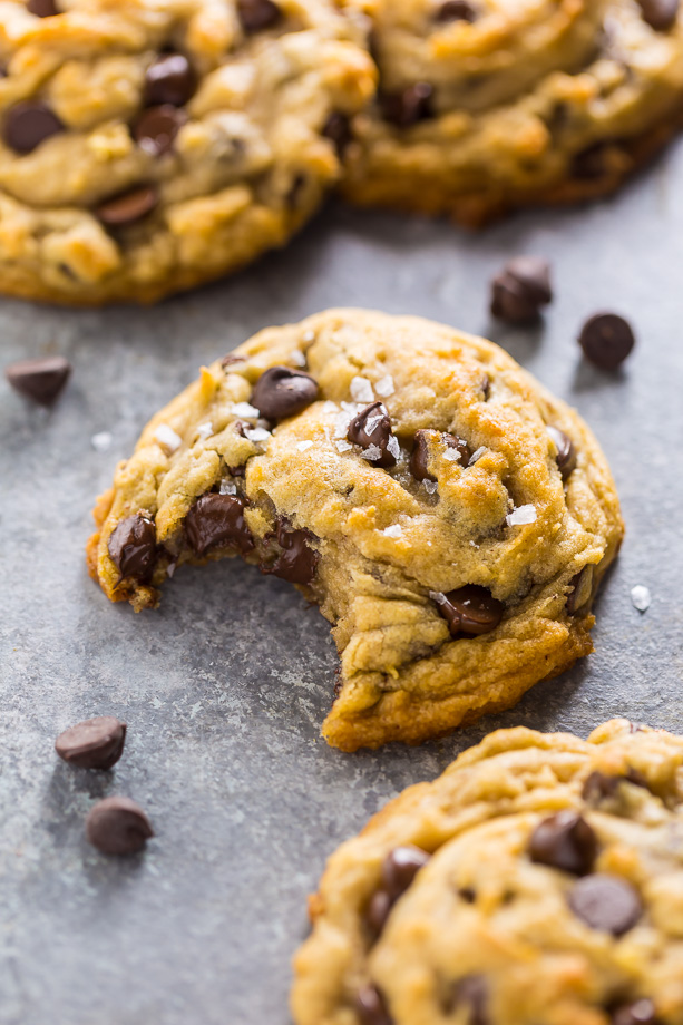 Vegan chocolate chip cookie on a blue table with a bite taken out.