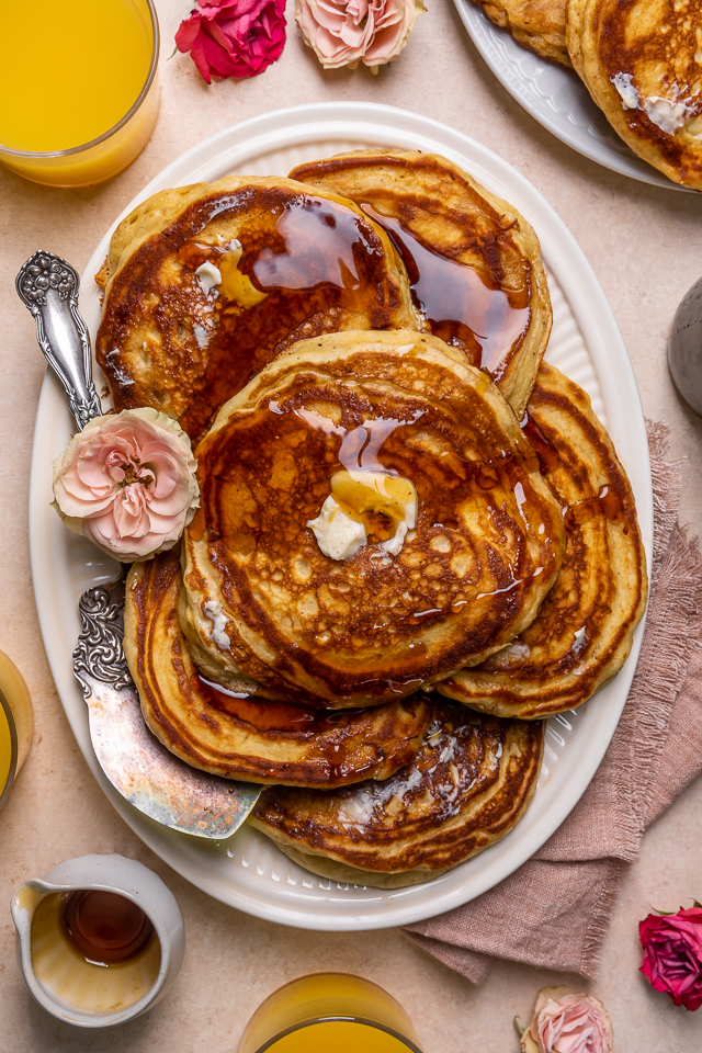 Serving platter with buttermilk pancakes covered in maple syrup.