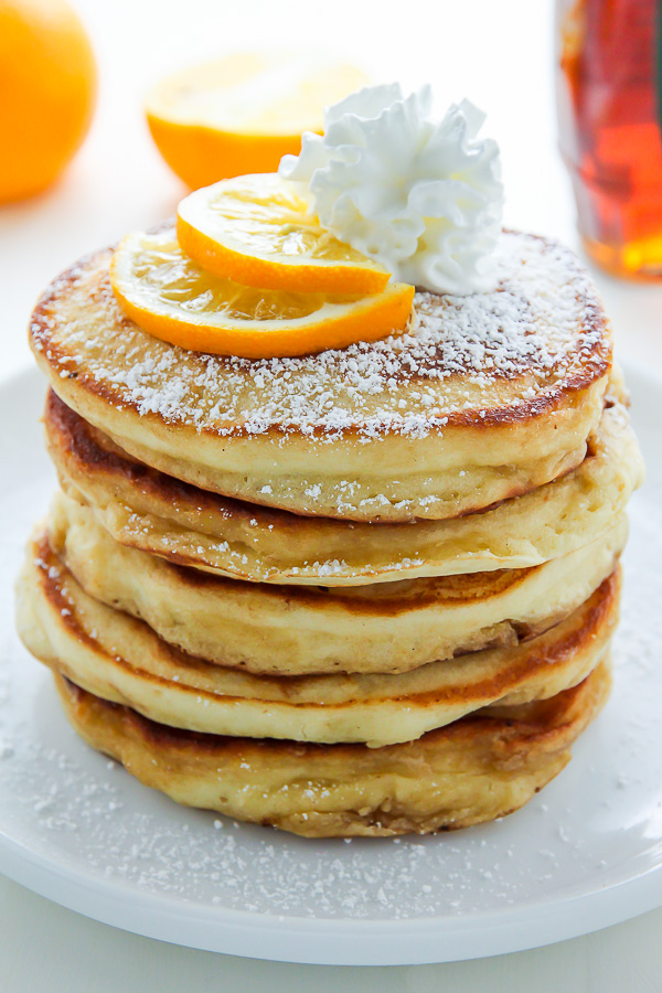A stack of lemon ricotta pancakes with whipped cream on top.