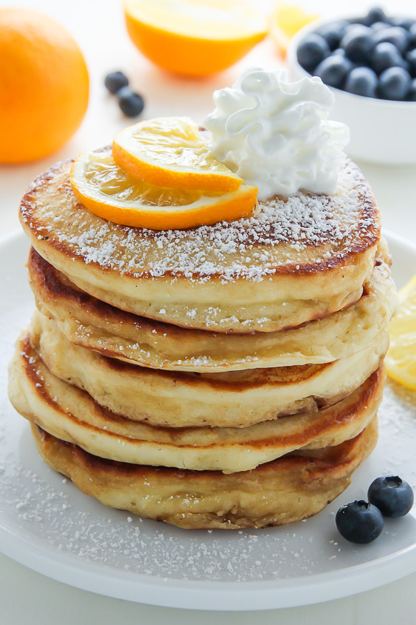 A stack of lemon ricotta pancakes with whipped cream on top.