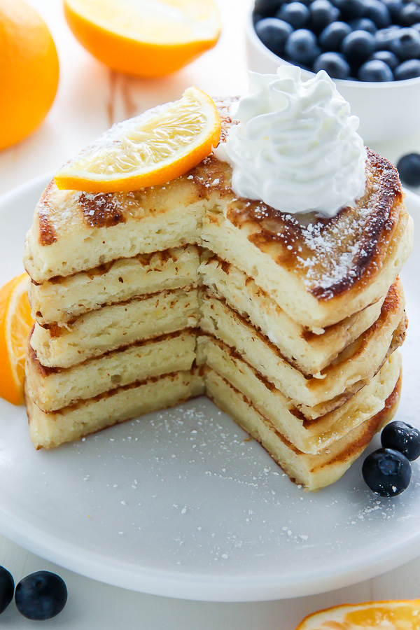 A stack of lemon ricotta pancakes with whipped cream on top.