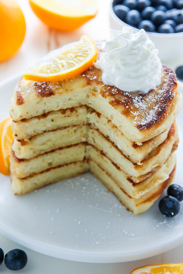 A stack of lemon ricotta pancakes with whipped cream on top.