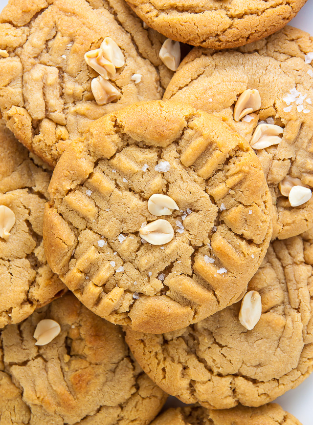 Pile of peanut butter cookies with chopped peanuts on top.