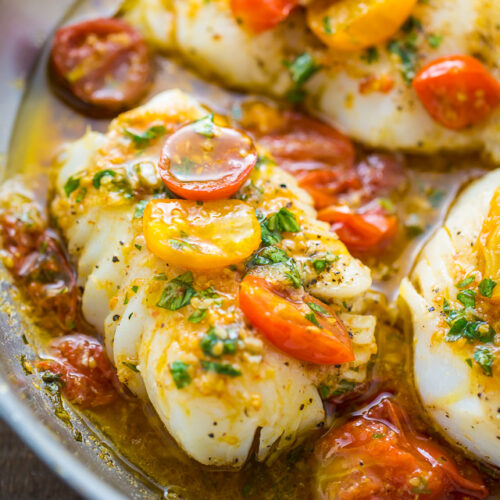 Pan-seared cod fish in a skillet covered with tomato basil sauce.