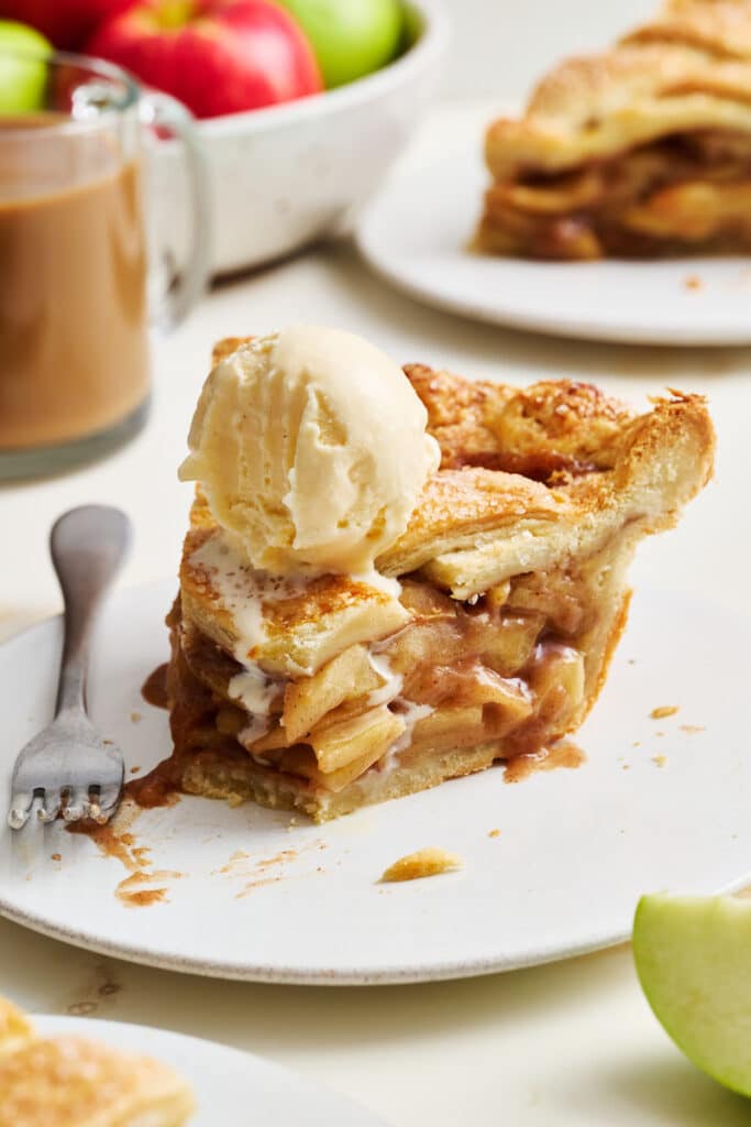 Slice of apple pie with ice cream on top.