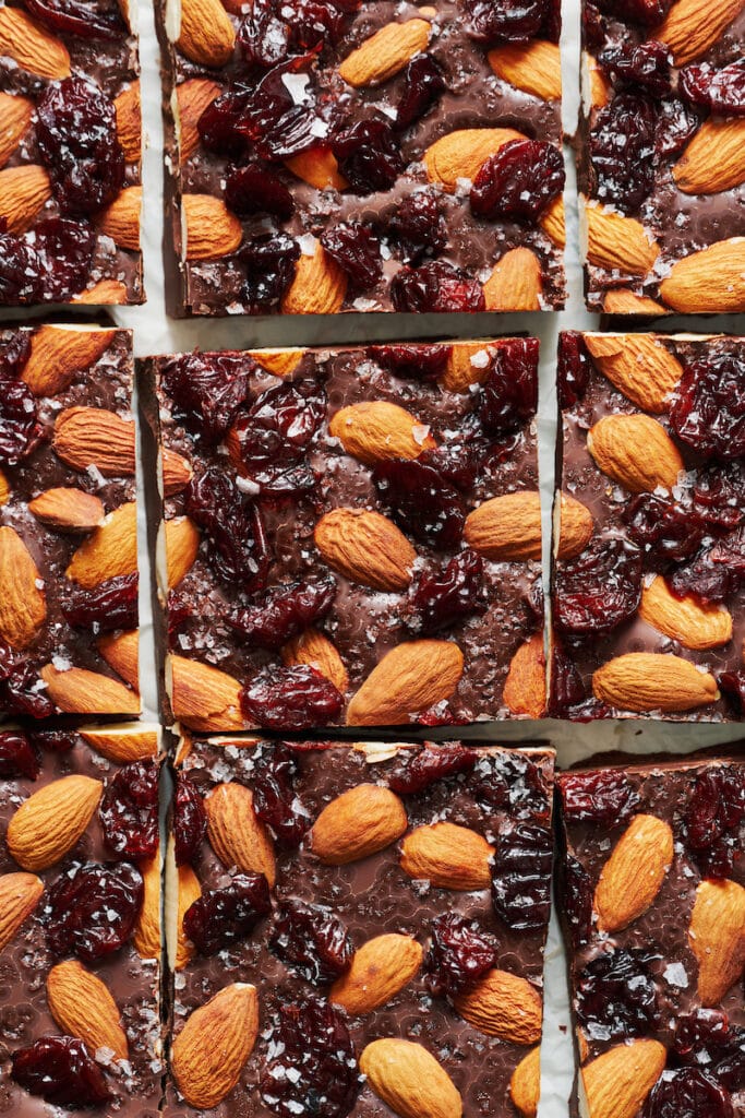 Chocolate bark cut into squares and topped with almonds and dried cranberries.