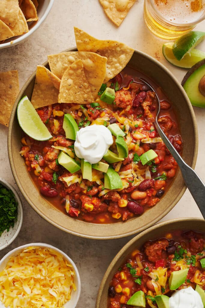 Bowl of turkey chili with tortilla chips and lime wedges.