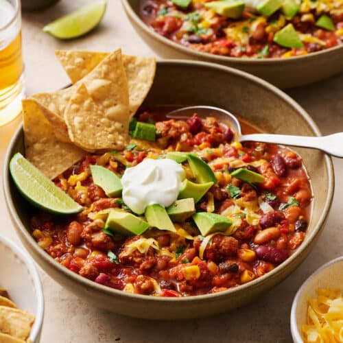 Turkey chili in bowls with tortilla chips, avocado, and sour cream.