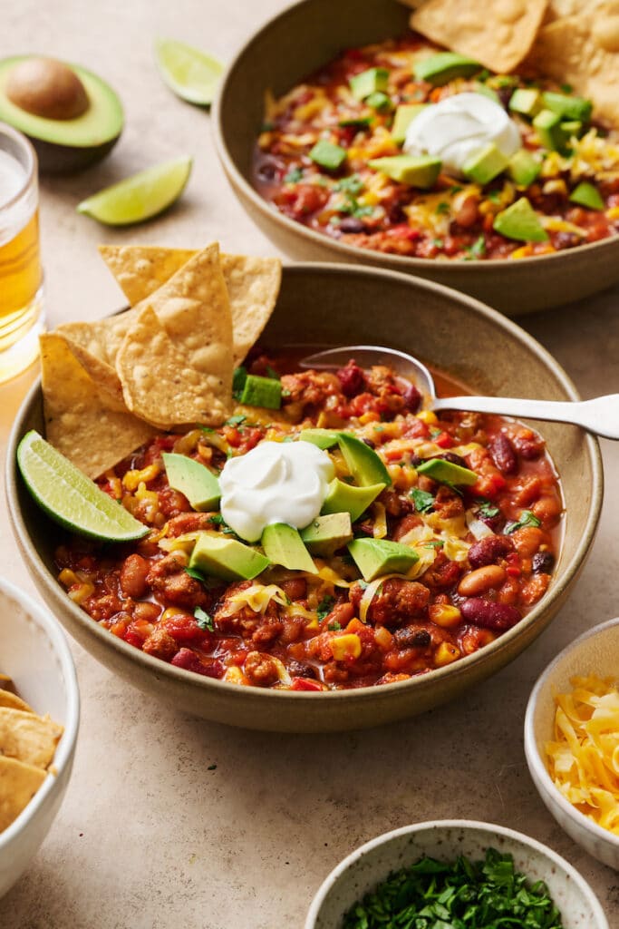 Turkey chili in bowls with tortilla chips, avocado, and sour cream.
