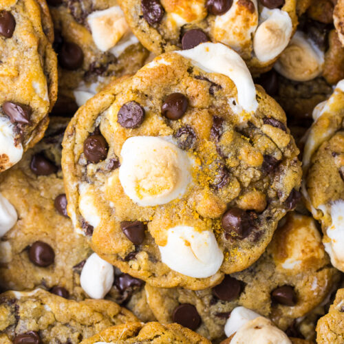 S'mores Chocolate Chip Cookies piled on top of each other with mini marshmallows on top.