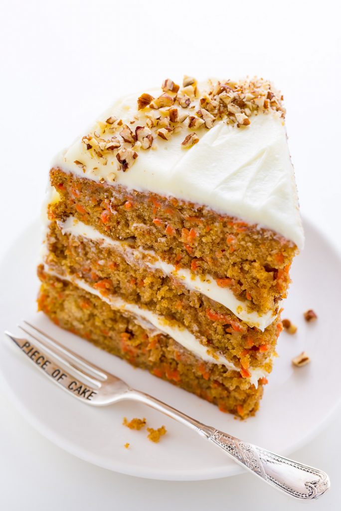 Slice of carrot cake on a white plate and dessert fork on the side.