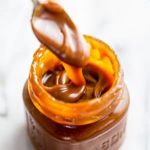 Jar of homemade salted caramel sauce with a spoon in it.
