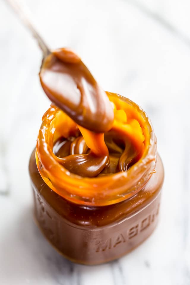 Jar of homemade salted caramel sauce with a spoon in it.