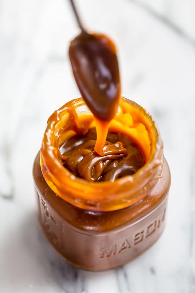 Jar of homemade salted caramel sauce with a spoon in it.