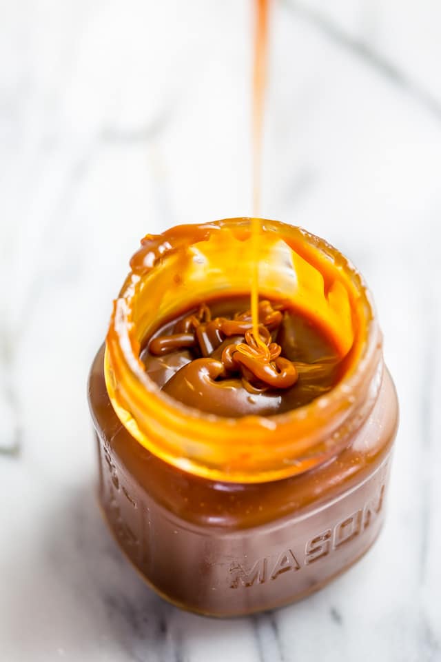 Jar of homemade salted caramel sauce with a spoon in it.