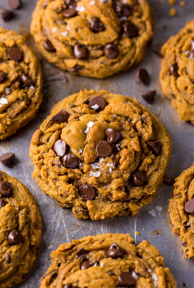 Freshly baked pumpkin chocolate chip cookies on a stainless steel baking sheet.