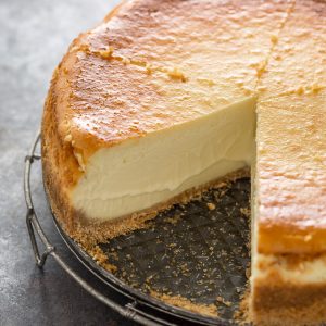 Thick style cheesecake on a spring form pan with a slice taken out.