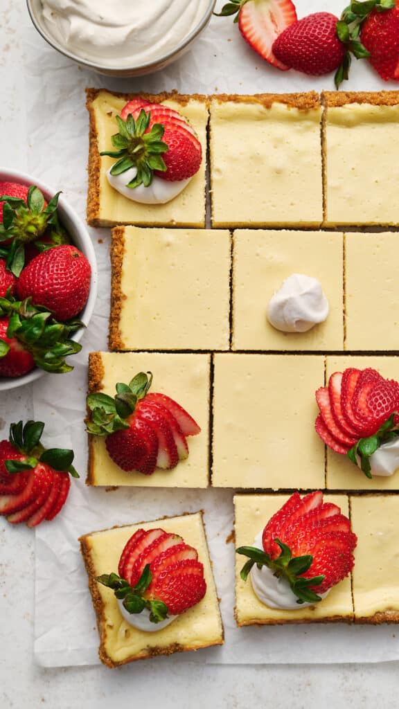 New York-Style Cheesecake Bars have a classic cheesecake filling and crunchy graham cracker crust! Full-fat cream cheese and sour cream are the secret to an ultra creamy cheesecake filling! Cut into squares and top with whipped cream and strawberries for a crowd-pleasing dessert everyone will love.