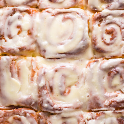 Cinnamon rolls in baking pan topped with sweet glaze.
