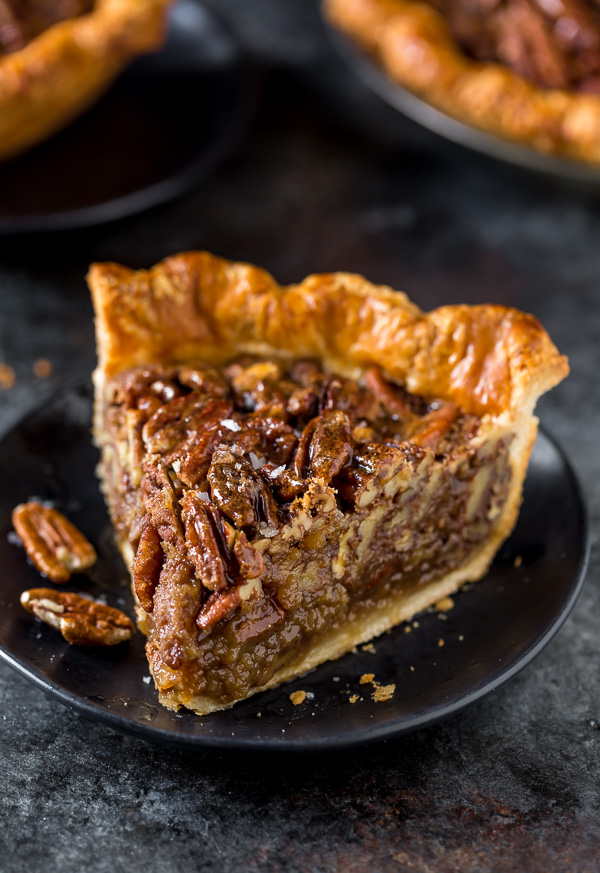 A slice of pecan pie on a black plate.