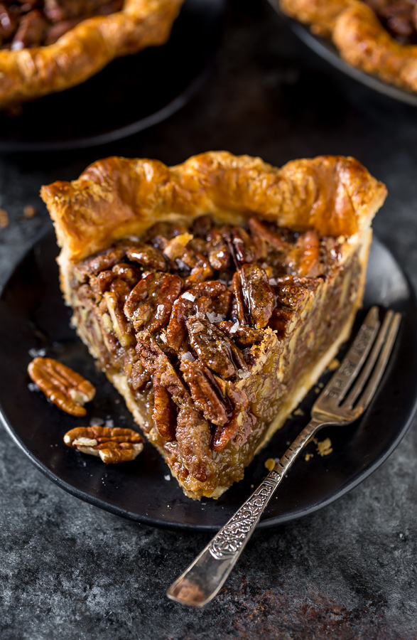 Slice of homemade pecan pie on a black plate.