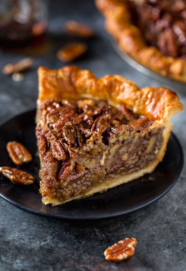 A slice of pecan pie on a black plate.