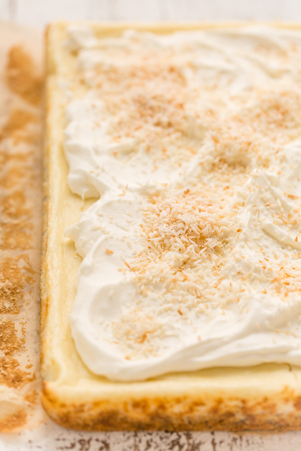 These Coconut Cheesecake Bars are creamy, sweet, and loaded with real coconut in every bite! Baked in cake pan and no water bath required, this recipe is easy and delicious! This family friendly recipe is always a crowd pleaser.