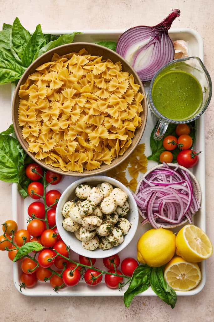 Salad ingredients for pasta salad on large baking pan.