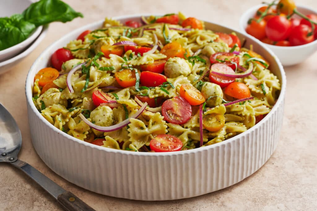 Big bowl of pasta salad with cherry tomatoes on the side.