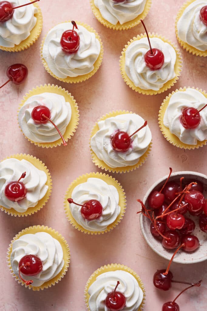 Ariel view of mini cheesecakes topped with whipped cream and cherries.