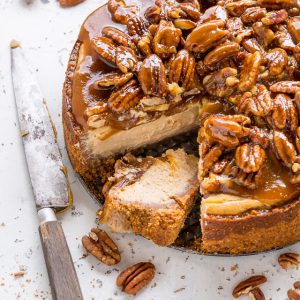 Pecan pie cheesecake with a slice cut out of it.