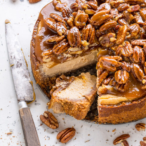 Pecan pie cheesecake with a slice cut out of it.