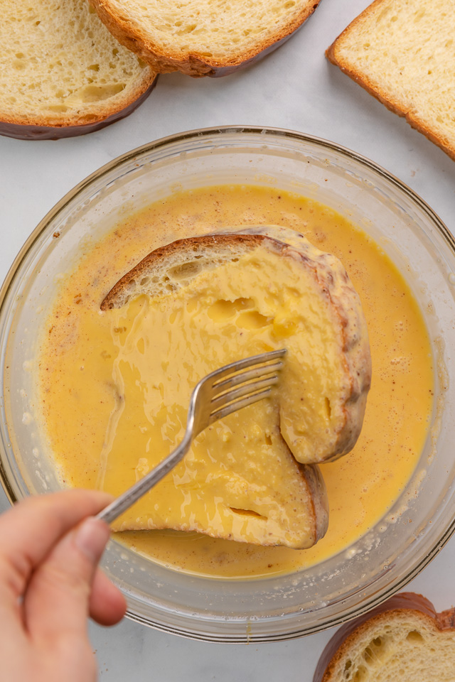 Dipping thick sliced bread into egg and milk mixture for French toast recipe.