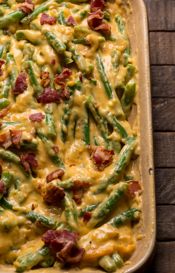 Green beans in baking dish covered with cheese sauce for green bean casserole recipe.