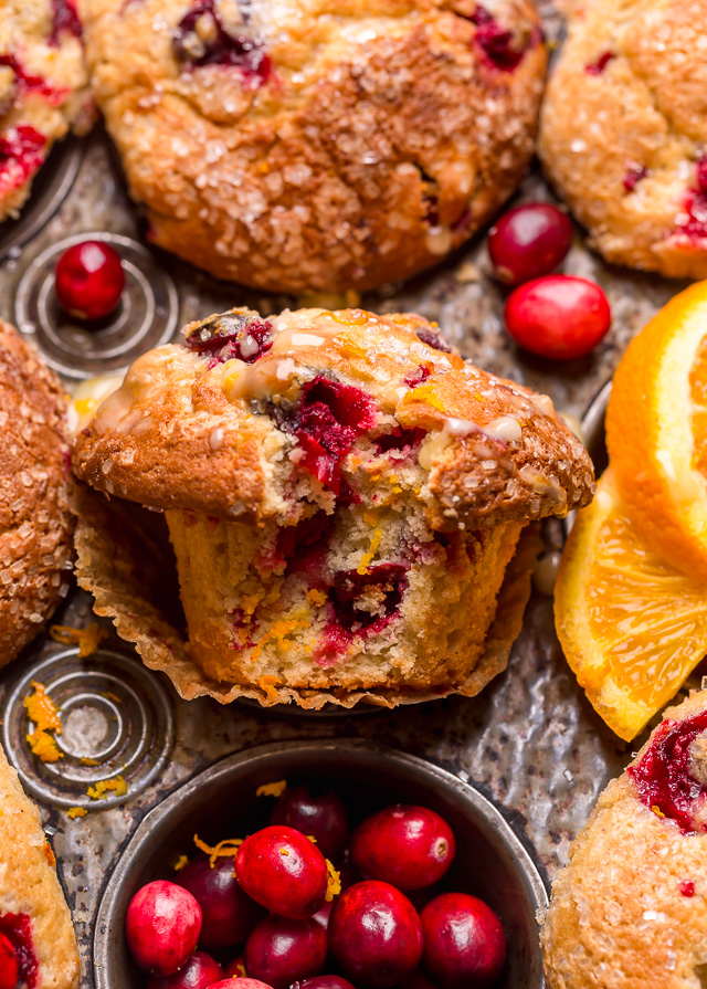 Cranberry orange muffin in a muffin tin with a bite taken out.