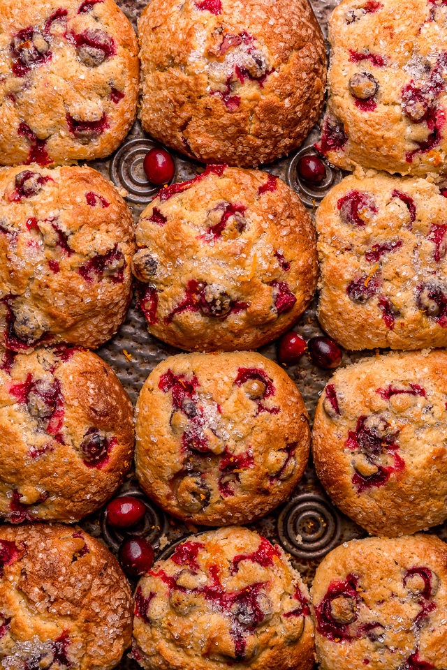 Cranberry orange muffins in a muffin pan with fresh cranberries and orange zest on top.