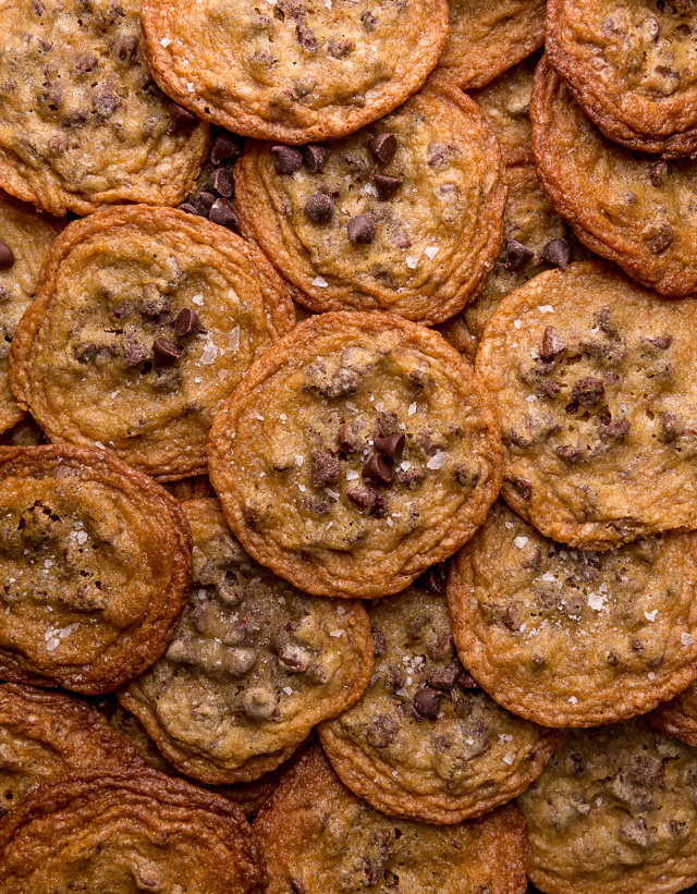 Pile of chocolate chip cookies with flaky sea salt on top.