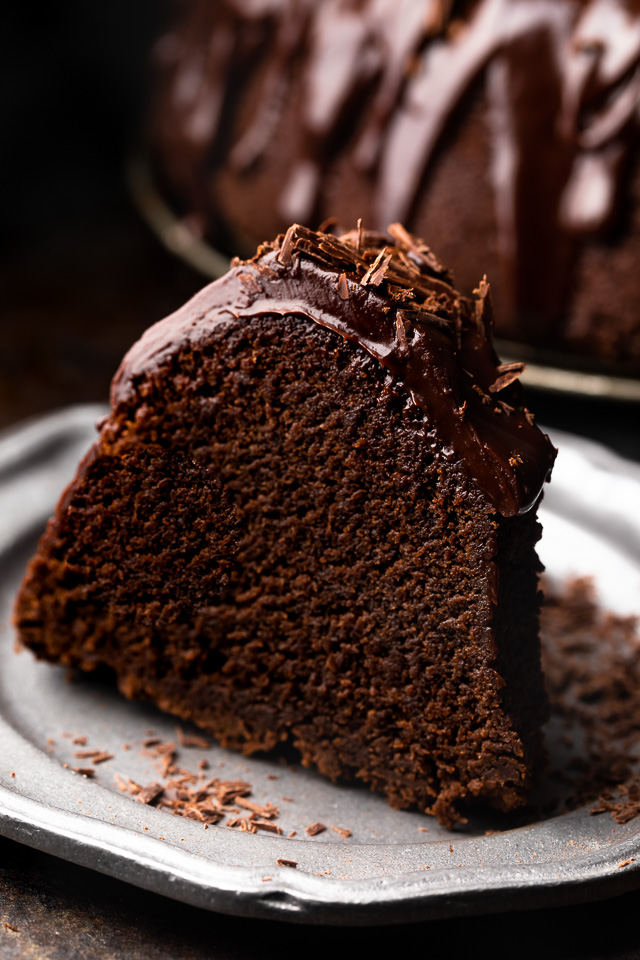 Slice of chocolate bundt cake covered in chocolate ganache on a plate.